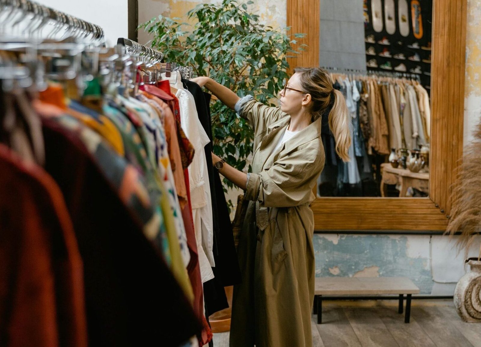 A stylish woman browsing clothes in a trendy boutique with wooden decor.