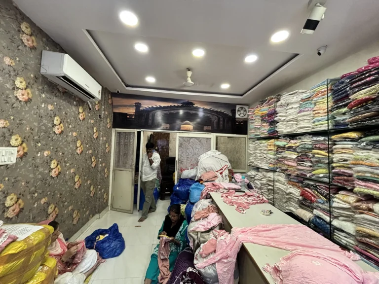 Smart Chikan Emporium showroom with stacked Chikankari garments and artisans at work