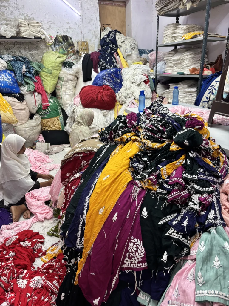 Artisans working among bundles of colourful Chikankari garments